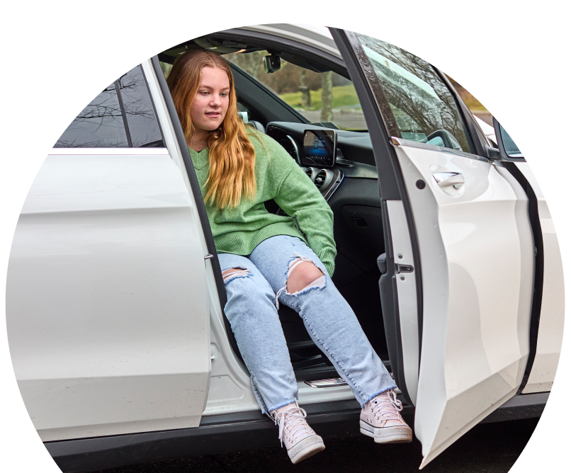 Mckenna seated inside a car with the door open